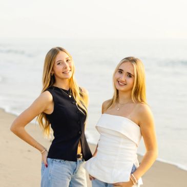 Two young women smiling at the beach.