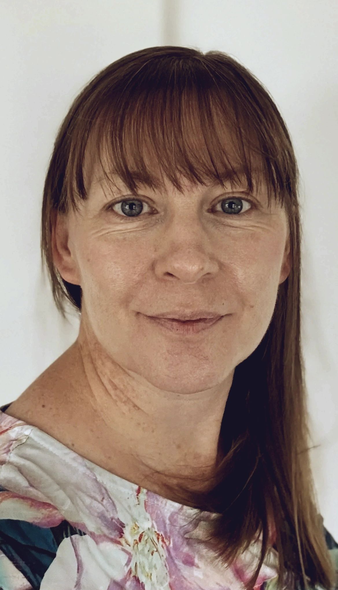 Close-up portrait of a woman with brown hair and bangs.