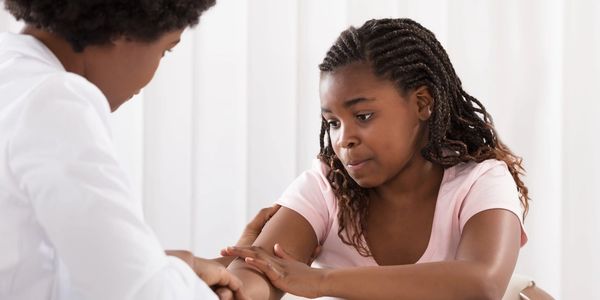 A young girl consulting a doctor, looking concerned.