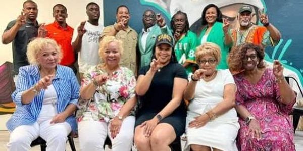 Group photo of diverse people smiling and posing with a peace sign.