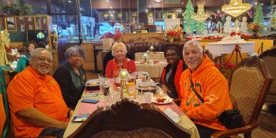 Group of five people dining together at a festive table.