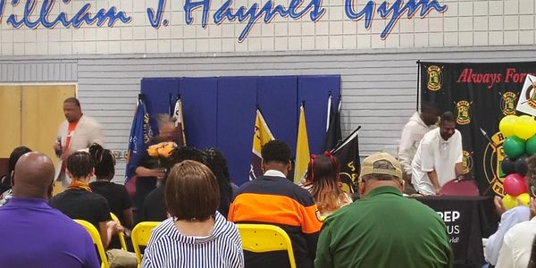 Community event in a gym with seated audience.