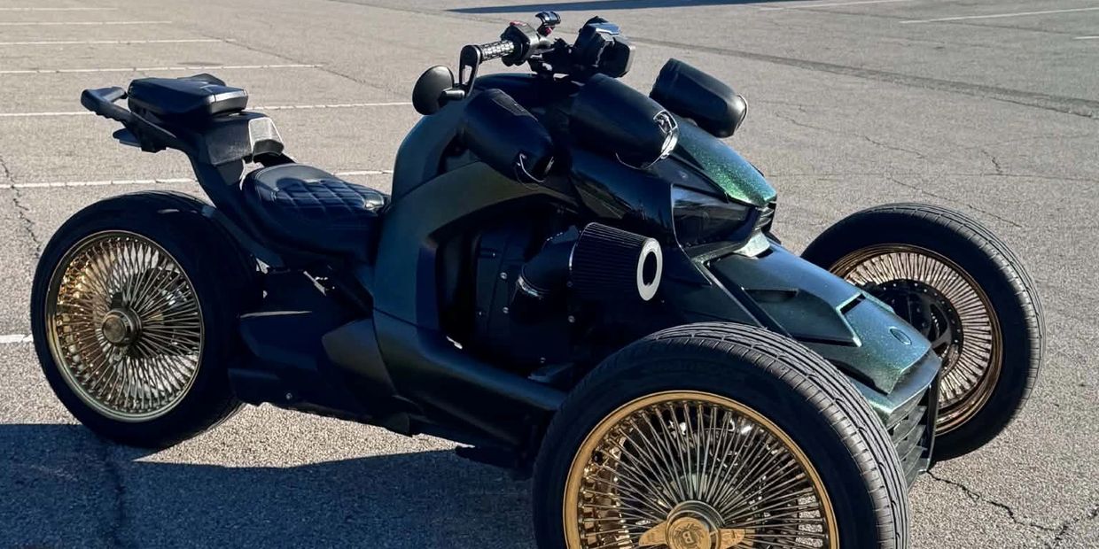 Unique three-wheeled custom bike with golden spoked wheels.