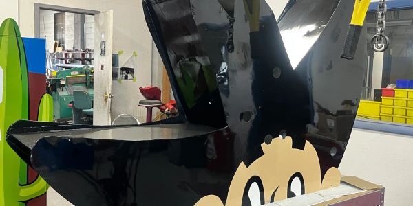 Large black metal letter W in a workshop.