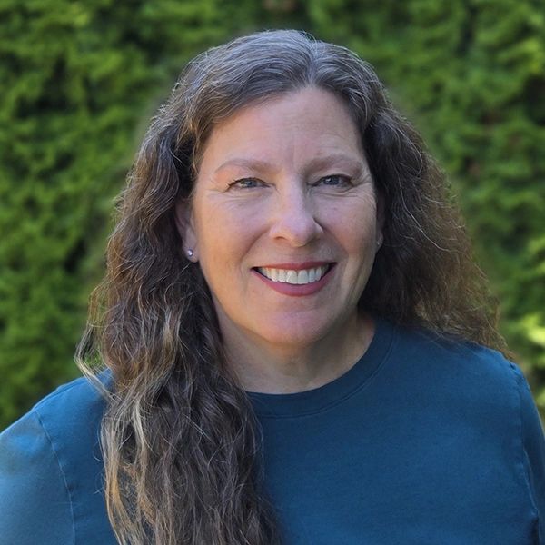 Smiling woman with long wavy hair outdoors.