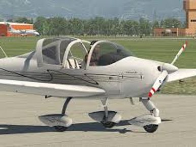 Small white light aircraft parked on runway near control tower.