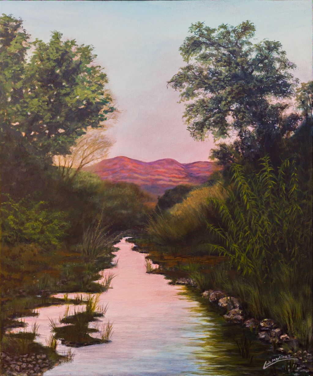 River flowing through dense greenery with mountains in the background.