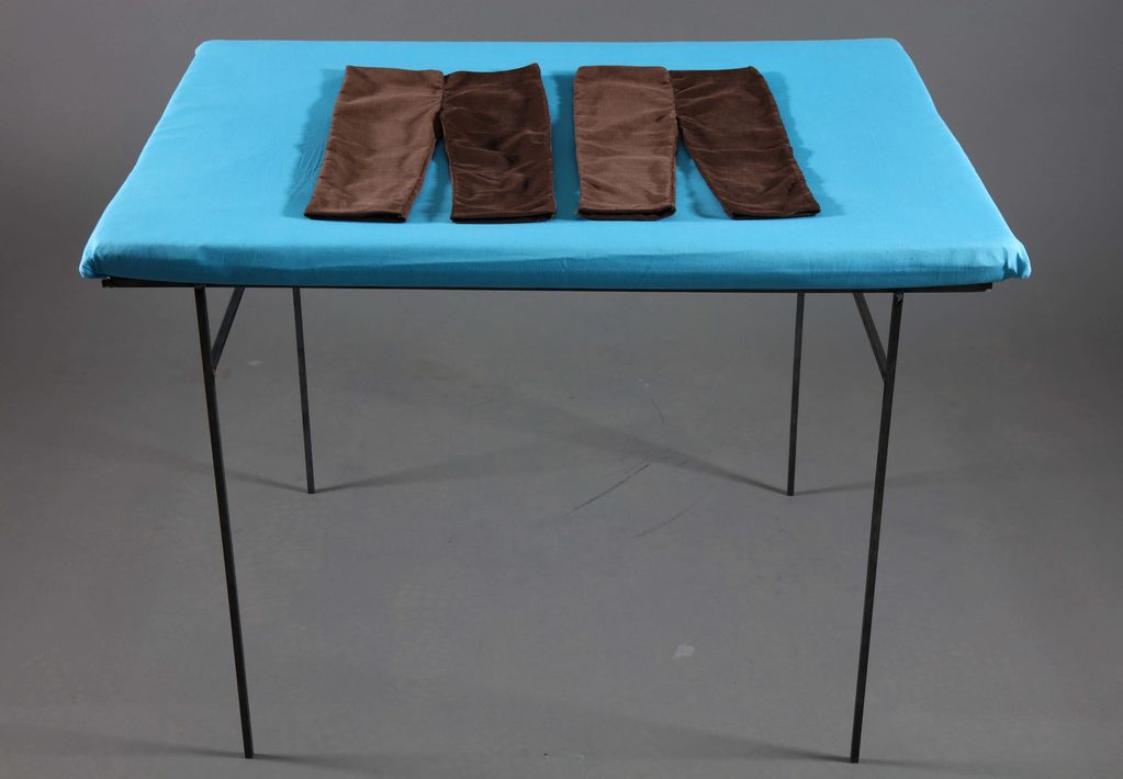 Two pairs of brown fabric folded on a blue-covered table.