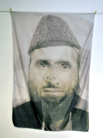 Portrait of a man with a cap on a hanging fabric.