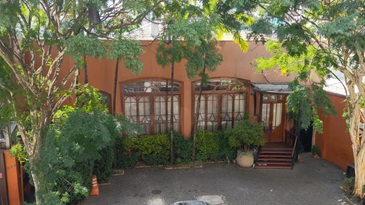 Fachada de casa laranja com árvores ao redor.