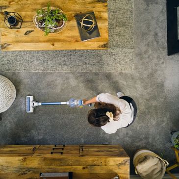 Person vacuuming a carpeted living room from above.