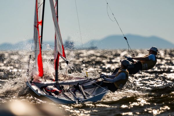 Two people sailing a small boat on choppy water.