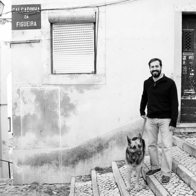 Man standing on tiled stairs with a German Shepherd.