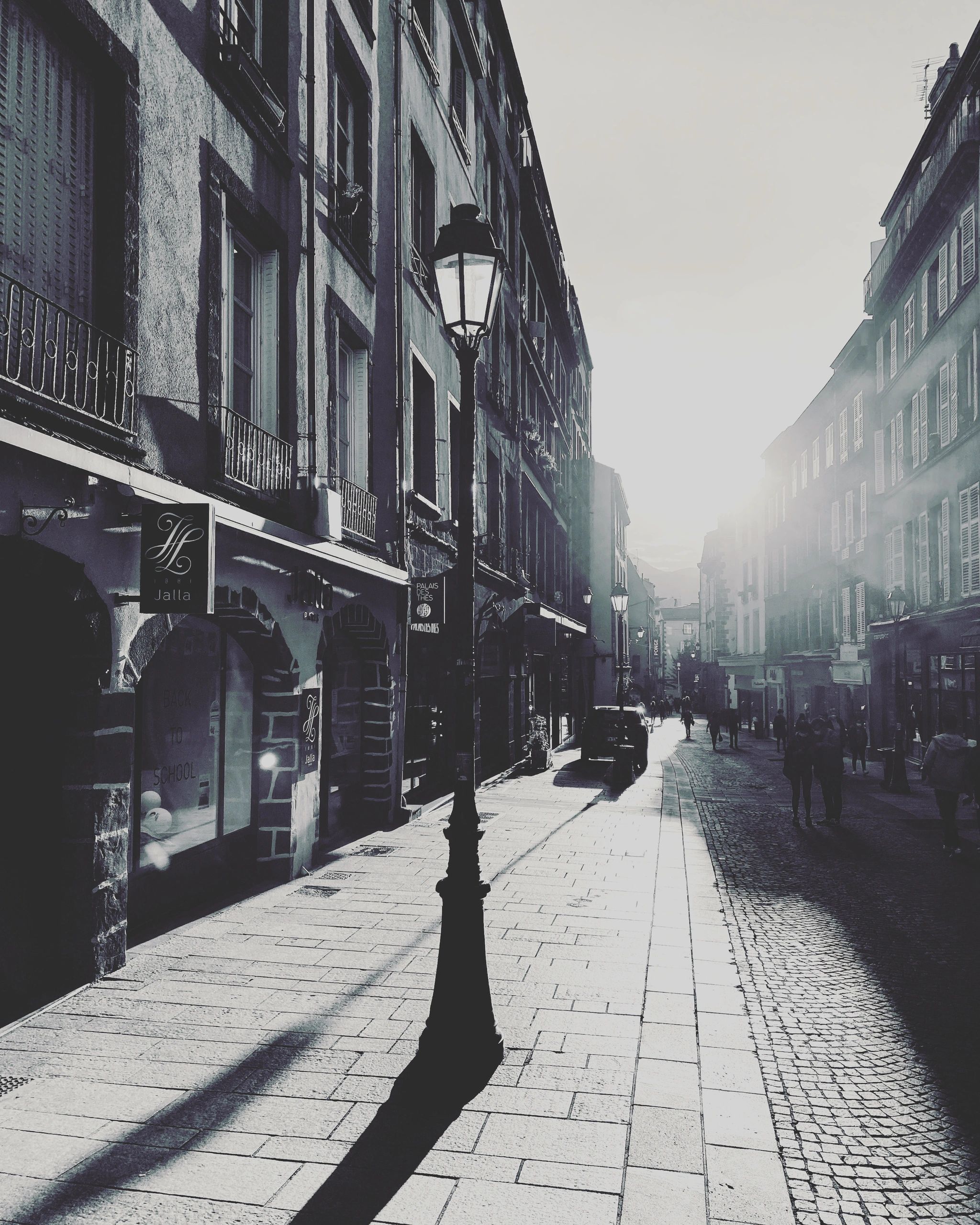 Sunlit old European street with vintage street lamps and shadows.