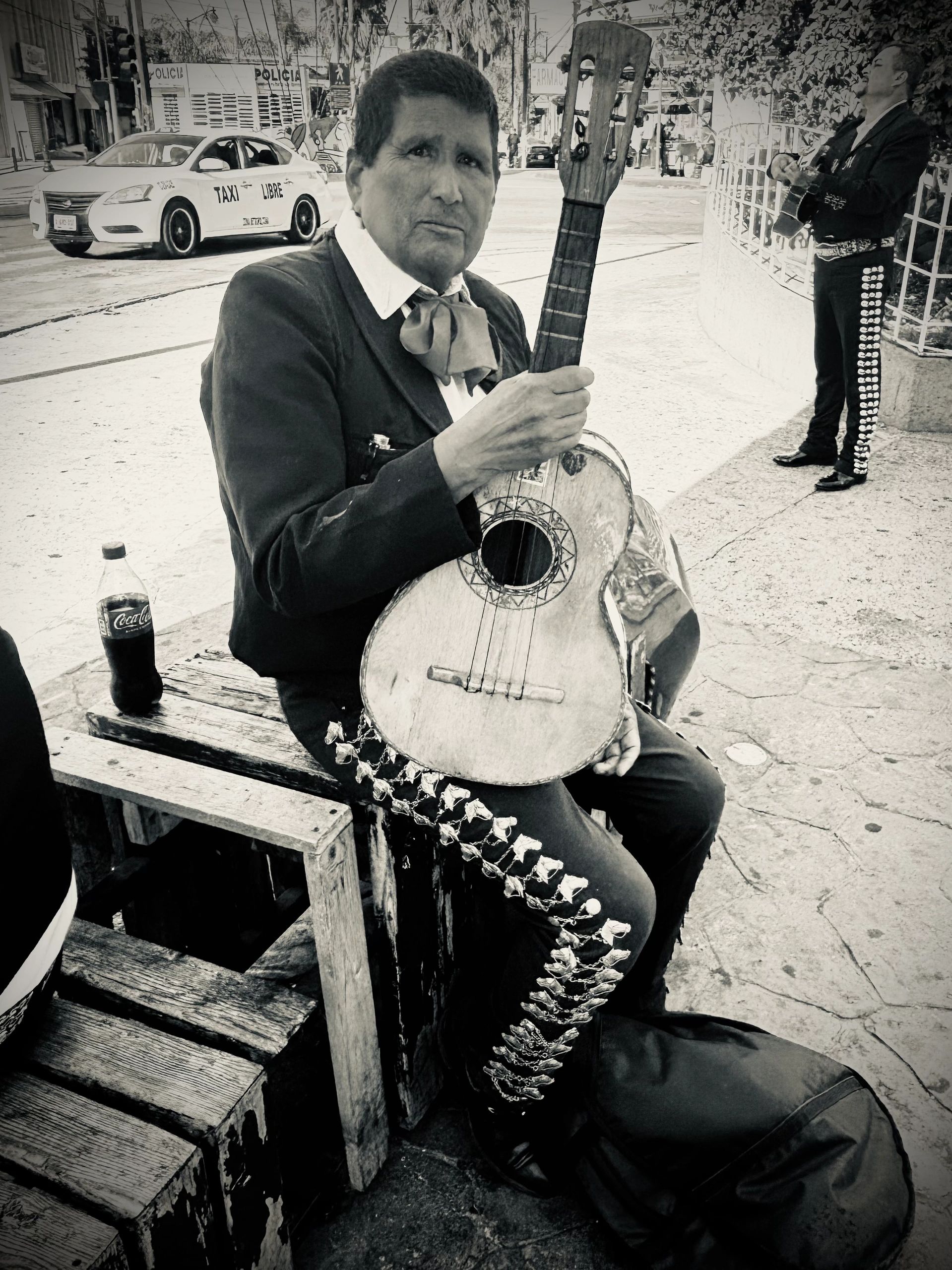 Black and white photo of a mariachi musician holding a guitar.