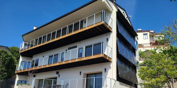 Modern multi-story house with large balconies and glass railings.