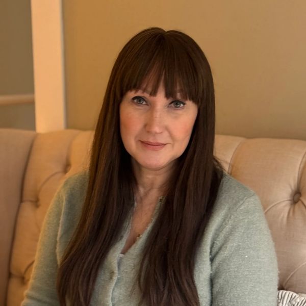 Counsellor and Psychotherapist in Aberdeen with long brown hair sitting at a table with a laptop.