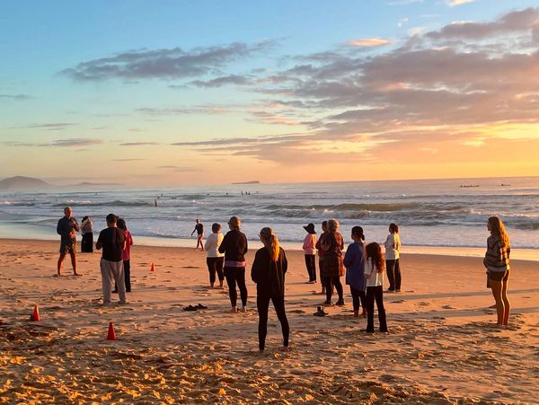 Group exercise class on the beach at sunset.