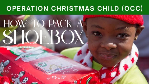 Child holding a decorated shoebox for Operation Christmas Child.