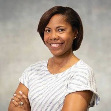 Confident woman smiling with arms crossed in casual attire.