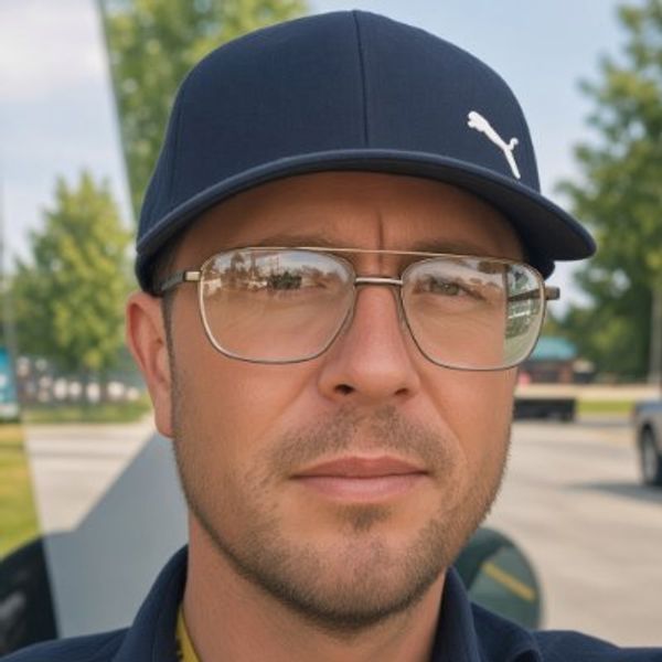 Man wearing glasses and a navy Puma cap.