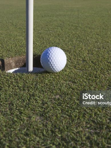 Golf ball near the hole on a green.