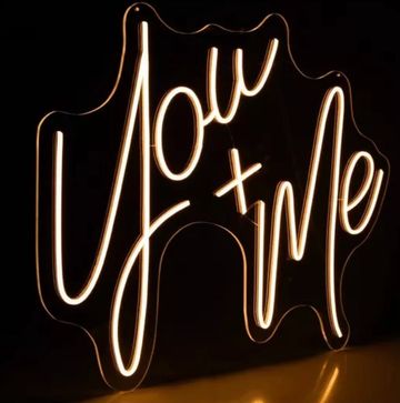 Neon sign glowing with the words 'You + Me' in cursive style.