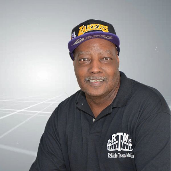 Man wearing a Lakers cap and RTM polo shirt smiles at the camera.
