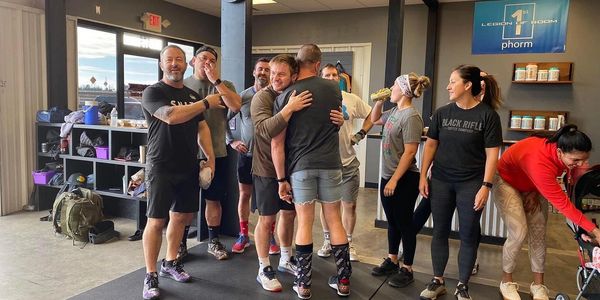 Group of people in a gym, some hugging, others chatting and preparing.