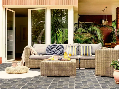 Cozy outdoor patio with wicker furniture and lush greenery.