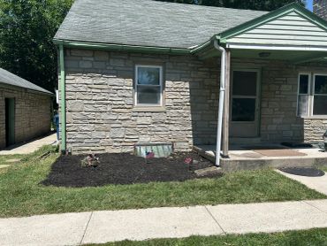 Stone house exterior with fresh mulch bed.