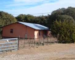 View of single story house with metal roof in fenced area.