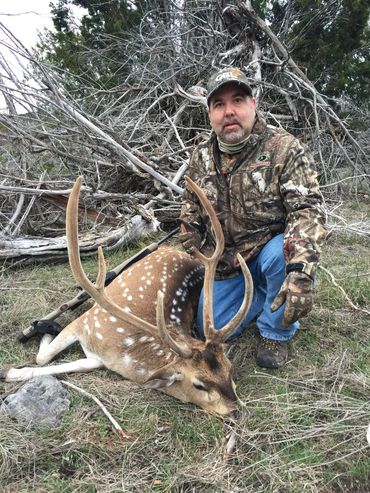 Hunter beside a large Axis Buck in velvet horn.