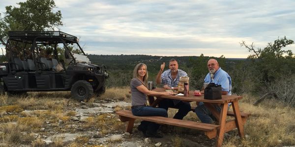 Visitors sitting on hilltop at picnic table.