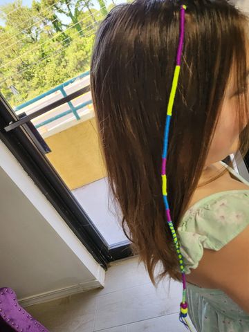 Hair wrap with friendship bracelet string, next to hair feathers