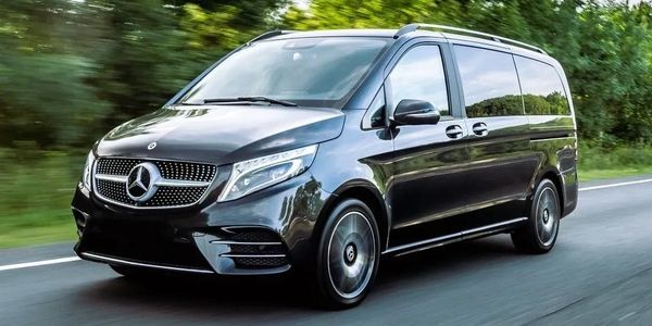 Black Mercedes-Benz luxury van driving on a road.