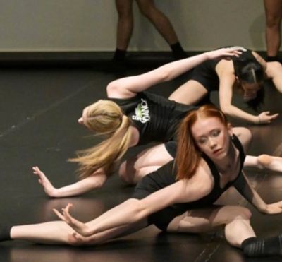 Dancers in a contemporary dance pose on stage.