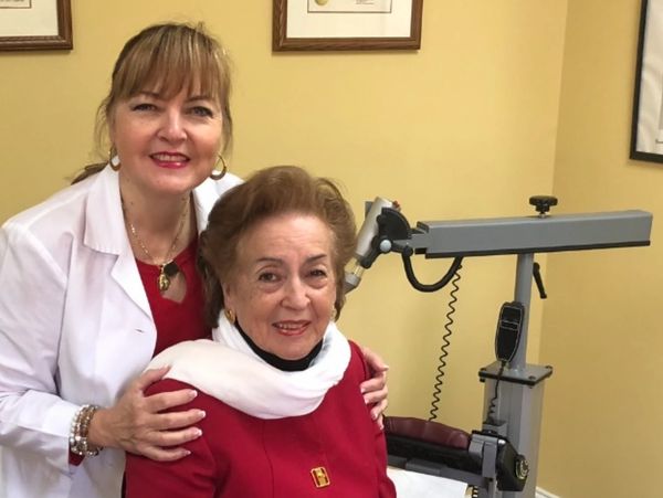 A doctor and elderly woman smiling in a medical office.