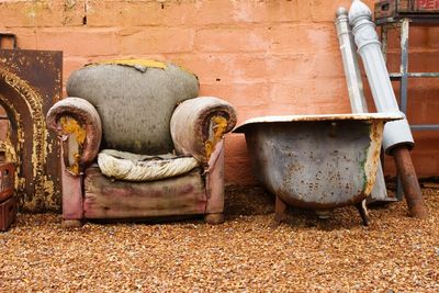 Old chair and tub leaning against a brick wall.