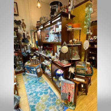 Cozy antique shop corner with vintage items and colorful rug.