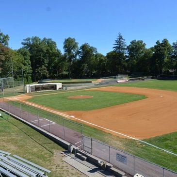 Empty baseball field with green grass and clear skies.