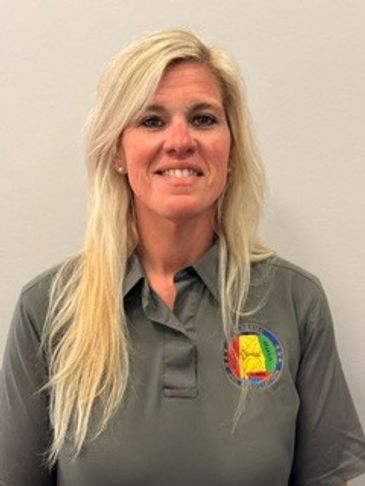 Smiling woman with long blonde hair in a gray polo shirt with a colorful embroidered logo.