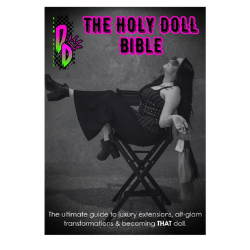 A stylish woman with long hair extensions poses on a chair for The Holy Doll Bible cover.