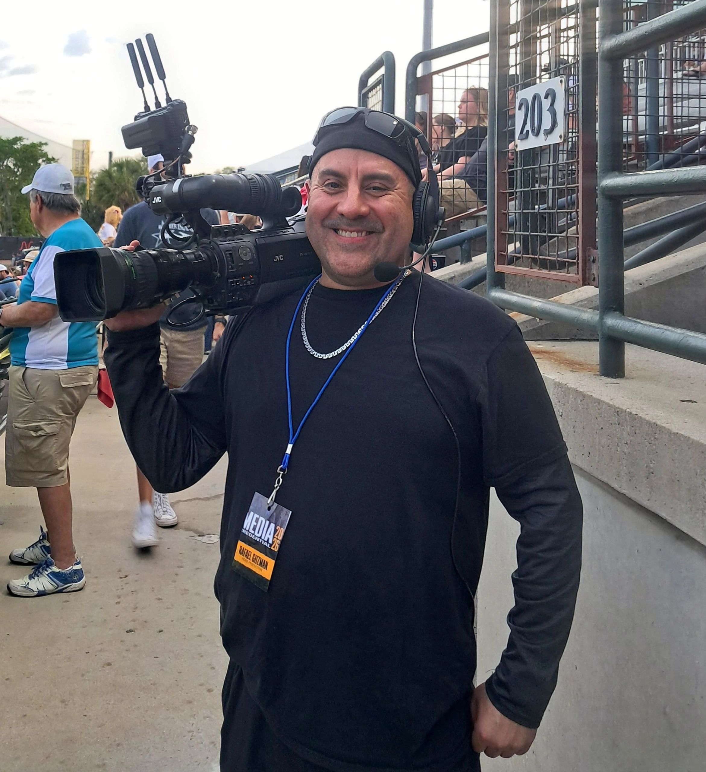 Smiling cameraman with headset at an outdoor event.