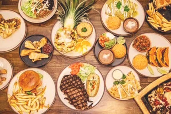 A diverse spread of grilled and fried dishes with sides on a wooden table.