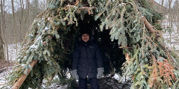 Child in a shelter built during our winter camps. Outdoor adventure in Durham Region, ON