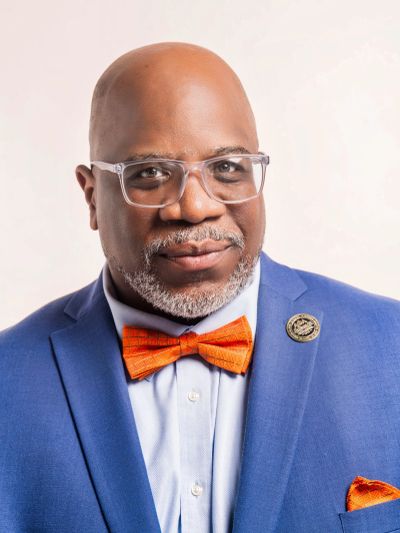 Man wearing a blue suit and orange bow tie.