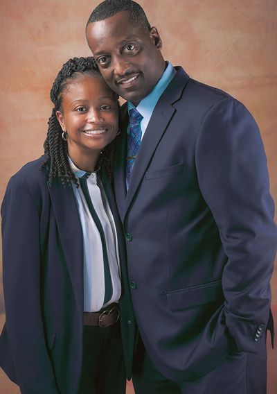 A smiling couple dressed in formal attire posing closely together.