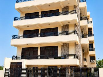 Modern multi-story residential building with balconies and black railings.
