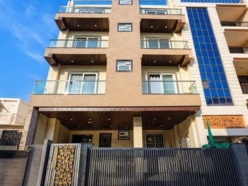 Modern multi-story residential building with balconies and a gated entrance.